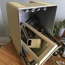 disassembled macintosh computer with its parts loosely contained in its case