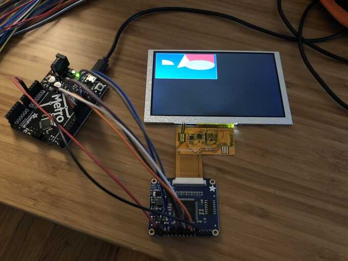 arduino with wires connecting to other board, which is connected to an LCD screen showing various shapes being drawn