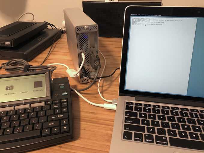 macbook connected to a thunderbolt enclosure, with cable connecting to mailstation, on a desk