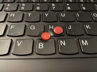 close-up of keyboard showing new trackpoint cap installed, with old cap next to it
